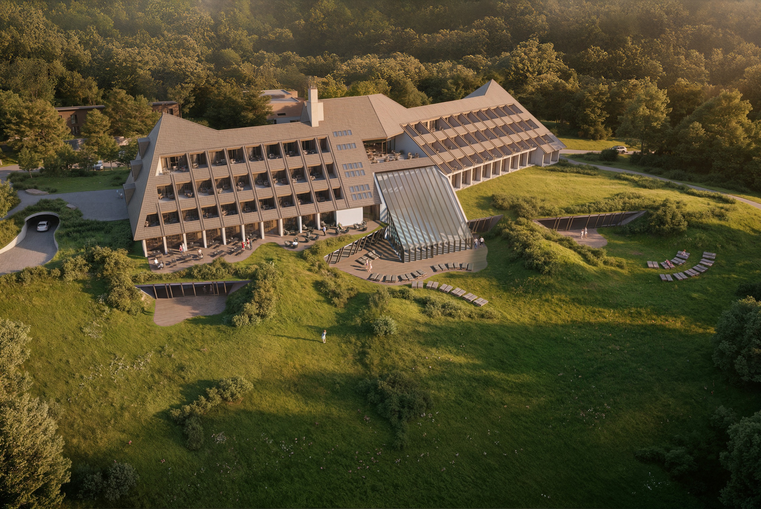 SPA Hotel Kanin Bovec seen from above at golden hour, its long terraced roof set into the forested slope above Bovec