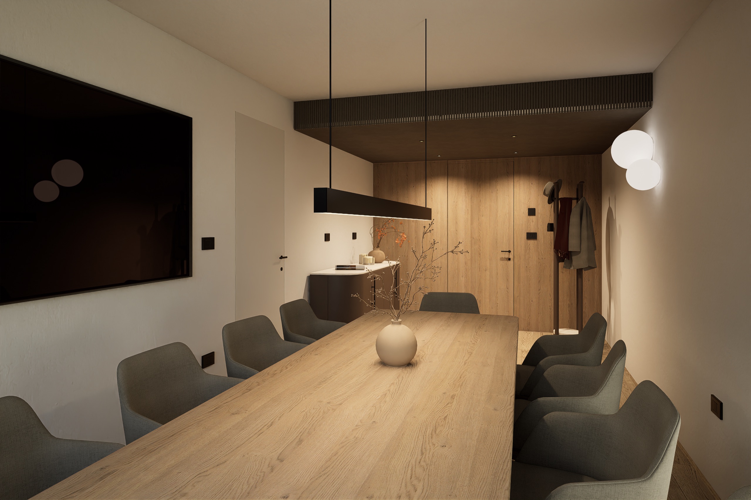 Long oak dining table with grey armchairs under a black pendant lamp, a wall TV and a coat rack by the door